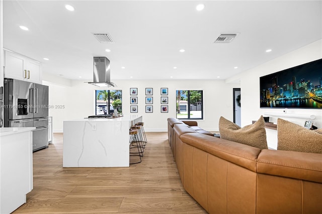 living area featuring light wood-type flooring, visible vents, and recessed lighting