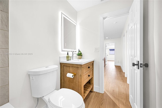 bathroom with toilet, wood finished floors, and vanity