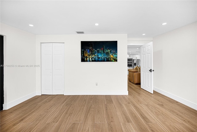 unfurnished room featuring visible vents, wood finished floors, baseboards, and recessed lighting