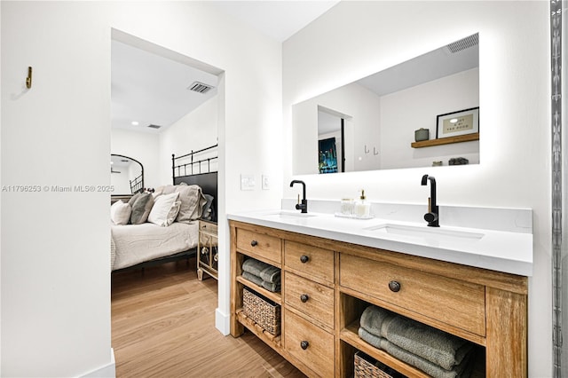 full bathroom featuring a sink, ensuite bathroom, visible vents, and wood finished floors