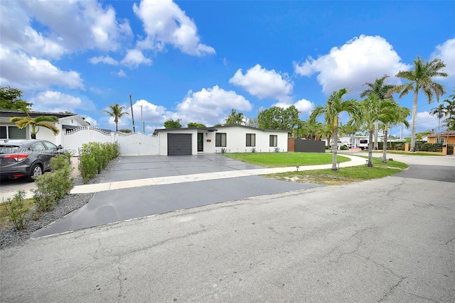 view of front of property with a front yard, aphalt driveway, an attached garage, and fence