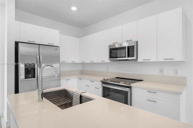 kitchen featuring a sink, white cabinetry, light countertops, appliances with stainless steel finishes, and recessed lighting