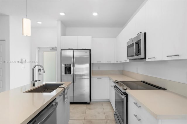 kitchen with light tile patterned floors, a sink, white cabinetry, light countertops, and appliances with stainless steel finishes