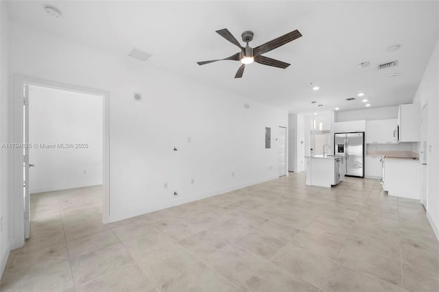 unfurnished living room with a sink, visible vents, recessed lighting, ceiling fan, and baseboards