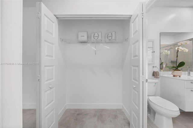 bathroom featuring vanity, toilet, and baseboards