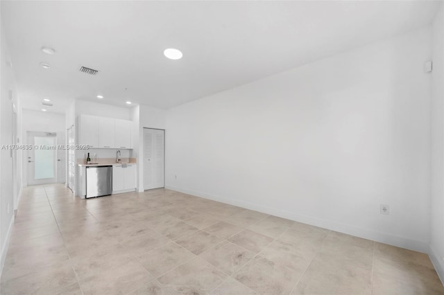 unfurnished living room with a sink, baseboards, visible vents, and recessed lighting