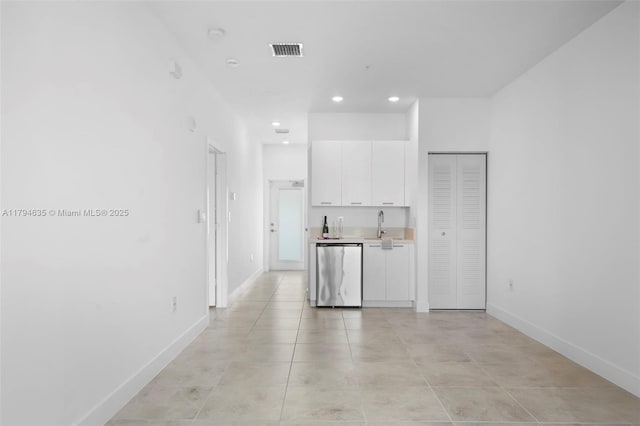 kitchen featuring a sink, white cabinets, stainless steel dishwasher, baseboards, and recessed lighting