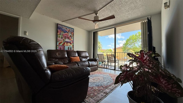 living area featuring floor to ceiling windows, a textured ceiling, wood finished floors, and a ceiling fan