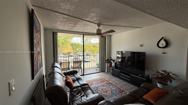 living room with a ceiling fan, a textured ceiling, and wood finished floors
