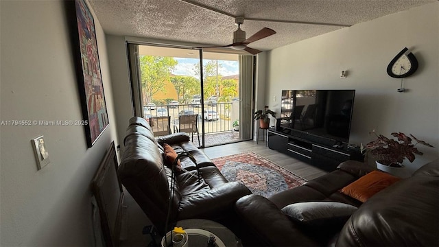 living room with a ceiling fan, expansive windows, a textured ceiling, and wood finished floors