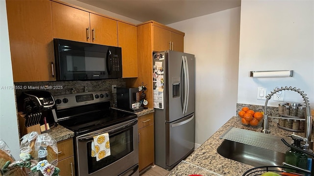 kitchen with a sink, brown cabinets, light countertops, tasteful backsplash, and appliances with stainless steel finishes
