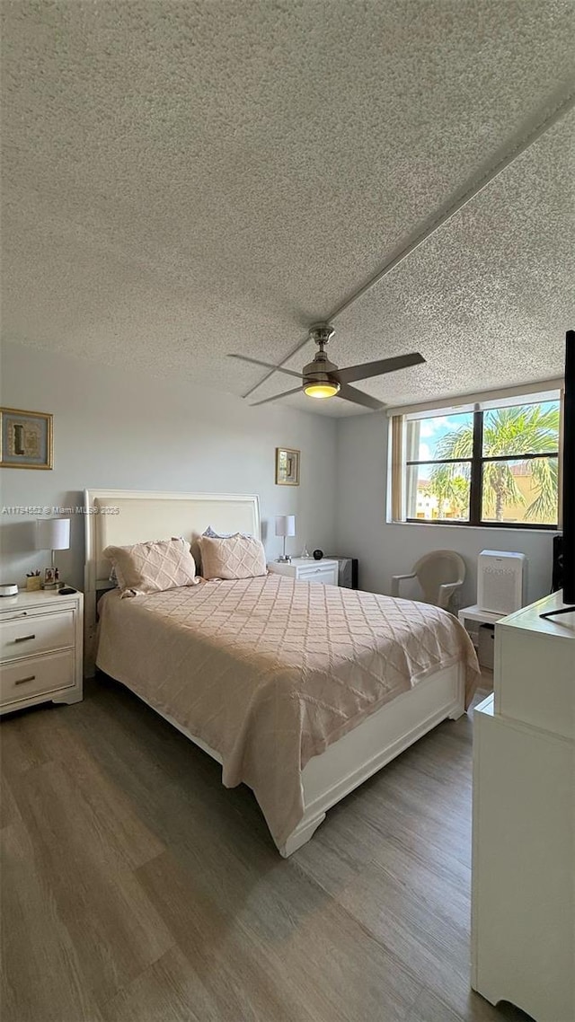 bedroom featuring dark wood finished floors, a ceiling fan, and a textured ceiling