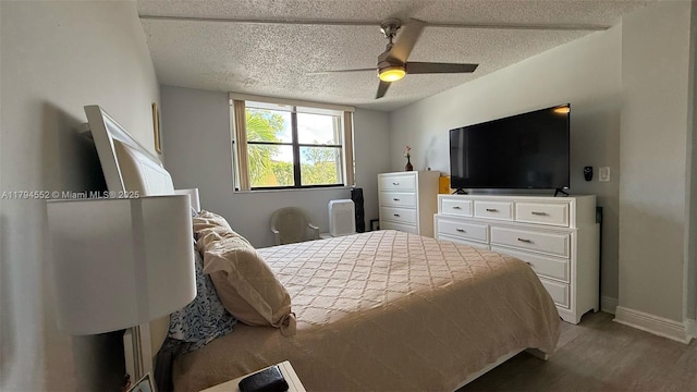 bedroom featuring ceiling fan, a textured ceiling, baseboards, and wood finished floors