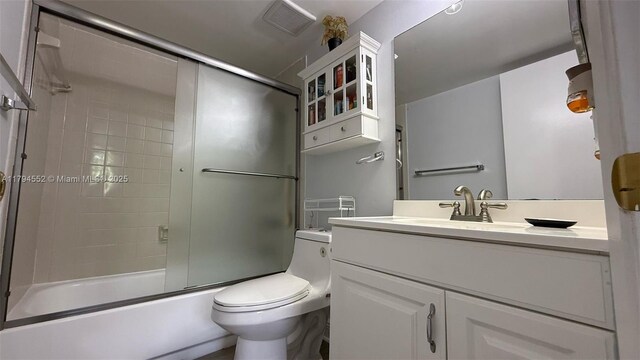 full bath with toilet, vanity, visible vents, and bath / shower combo with glass door