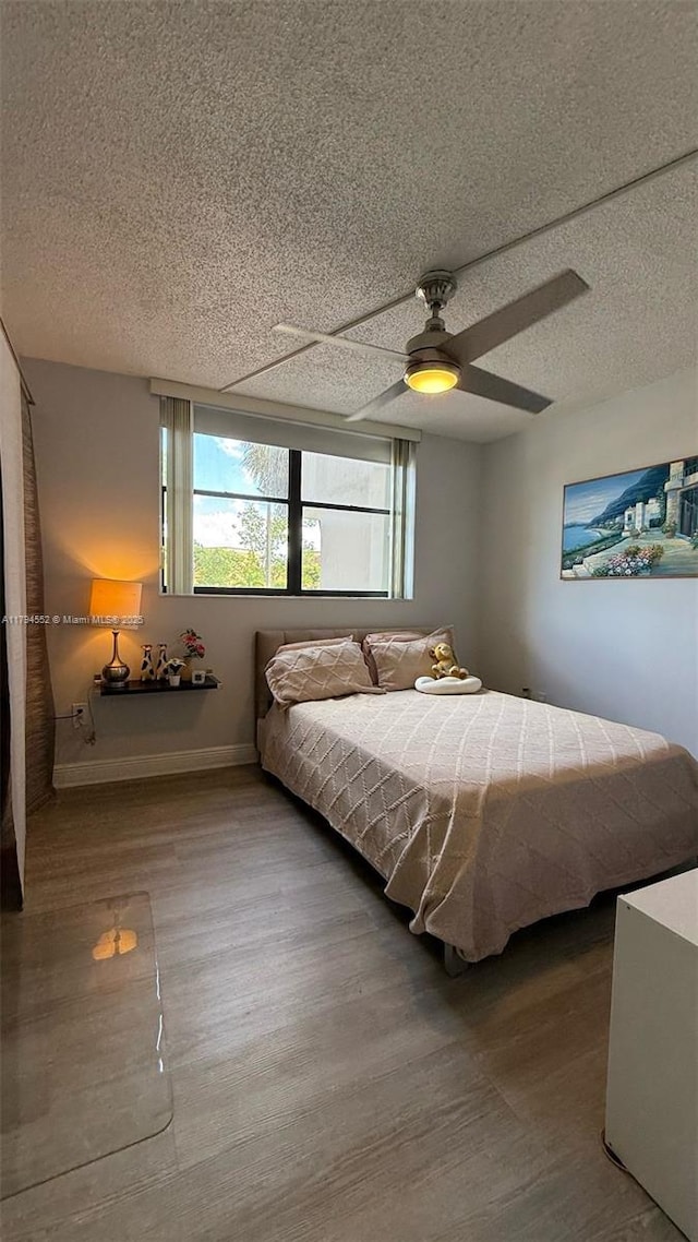 bedroom featuring a ceiling fan, multiple windows, and wood finished floors