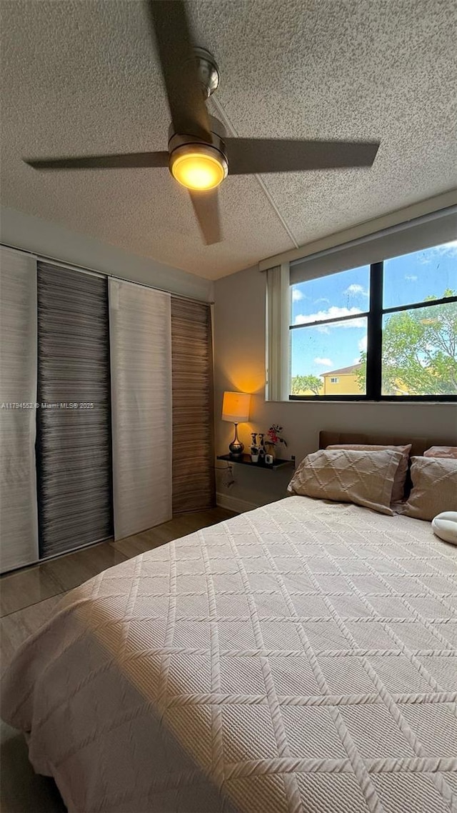 bedroom with ceiling fan, a textured ceiling, and wood finished floors