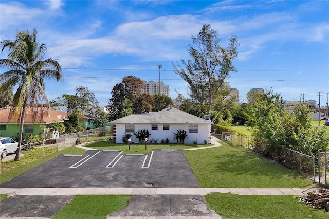 view of front of property featuring uncovered parking, fence, and a front lawn