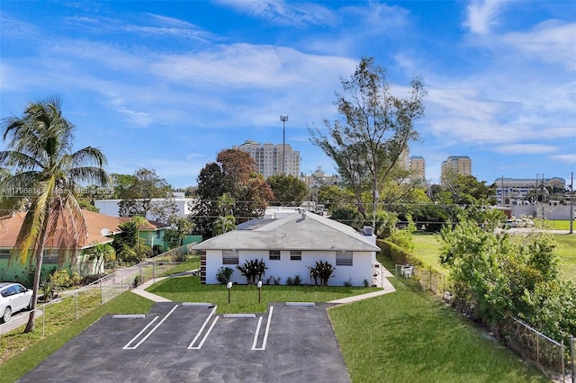 exterior space featuring uncovered parking, fence, and a yard
