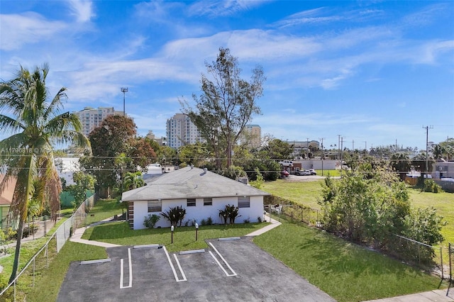 view of community with a yard, fence, and uncovered parking
