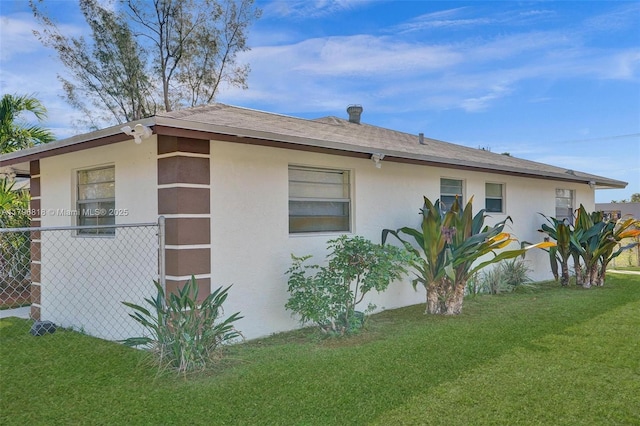 view of property exterior featuring stucco siding, fence, and a lawn