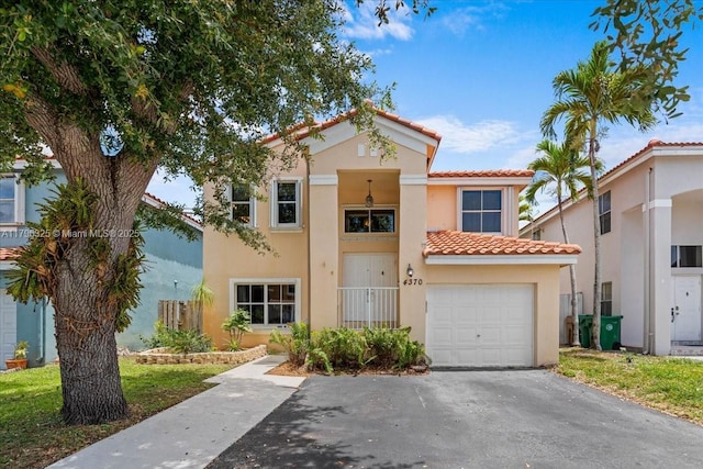 mediterranean / spanish-style house featuring driveway, stucco siding, a tile roof, and an attached garage