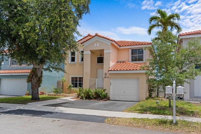 mediterranean / spanish house featuring aphalt driveway, a garage, a tiled roof, and stucco siding