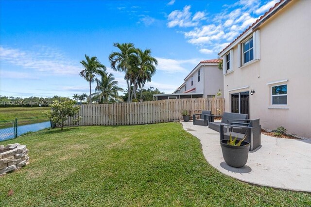 view of yard with a patio area, a water view, and a fenced backyard