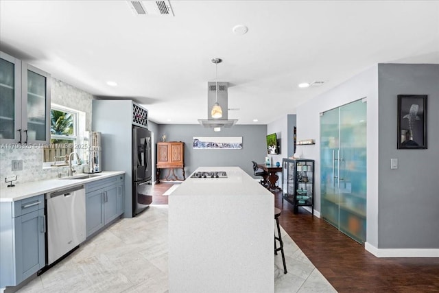 kitchen with glass insert cabinets, a sink, freestanding refrigerator, stainless steel dishwasher, and a kitchen island