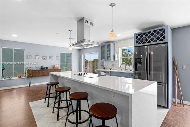 kitchen with a breakfast bar area, stainless steel appliances, range hood, light wood-type flooring, and recessed lighting