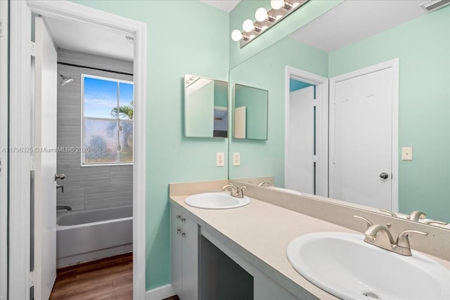 full bath with a sink, washtub / shower combination, visible vents, and wood finished floors