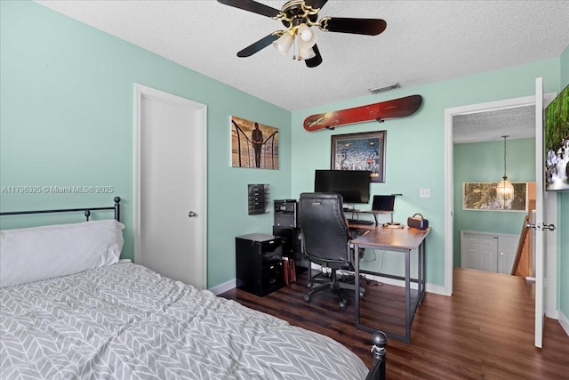 bedroom with a ceiling fan, a textured ceiling, baseboards, visible vents, and wood finished floors