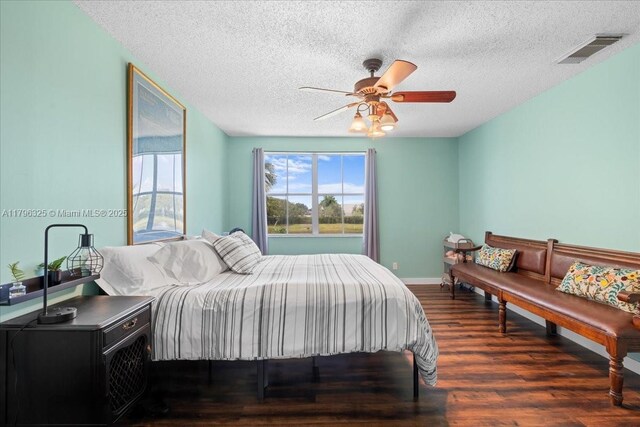 bedroom with wood finished floors, a ceiling fan, a textured ceiling, visible vents, and baseboards