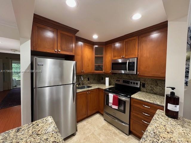 14 Westbury A 14, Deerfield Beach, FL 33442 - kitchen featuring a sink, stainless steel appliances, tasteful backsplash, light stone counters, and glass insert cabinets