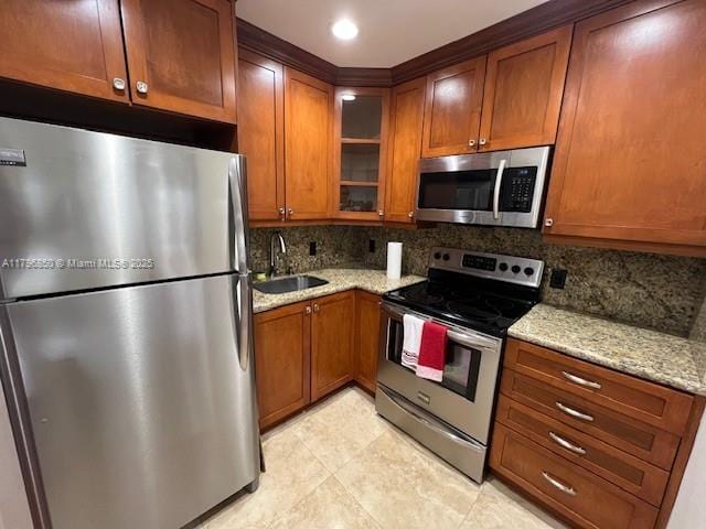 14 Westbury A 14, Deerfield Beach, FL 33442 - kitchen featuring a sink, brown cabinetry, light stone counters, decorative backsplash, and appliances with stainless steel finishes