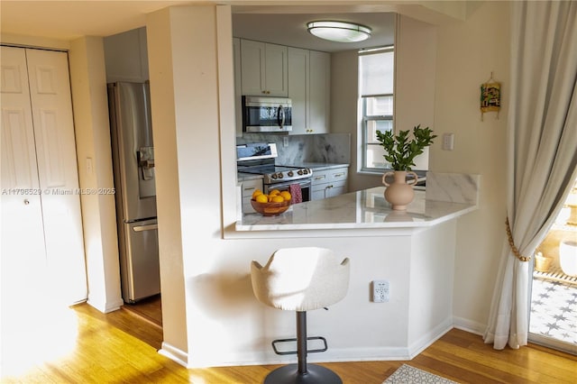 520 SE 5th Ave Unit 3302, Fort Lauderdale, FL 33301 - kitchen featuring a peninsula, light wood finished floors, backsplash, light countertops, and appliances with stainless steel finishes