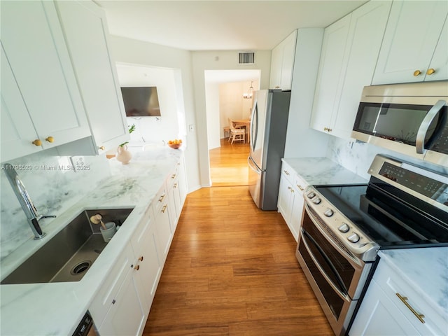 520 SE 5th Ave Unit 3302, Fort Lauderdale, FL 33301 - kitchen with light stone counters, visible vents, wood finished floors, stainless steel appliances, and white cabinets