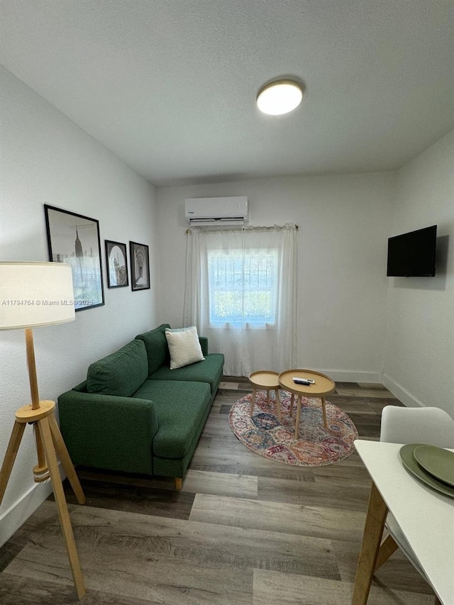 living room with wood finished floors, baseboards, and a wall unit AC