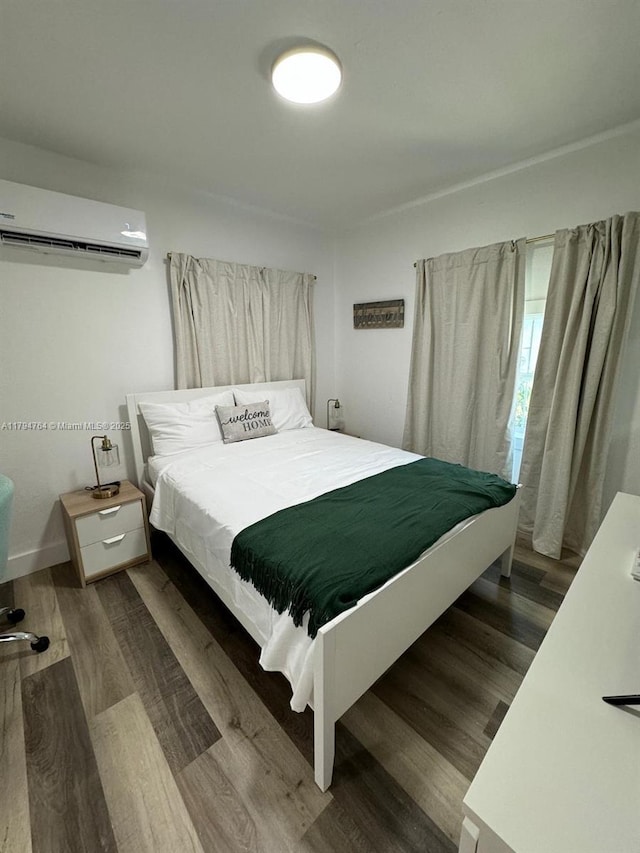 bedroom with a wall mounted AC and wood finished floors