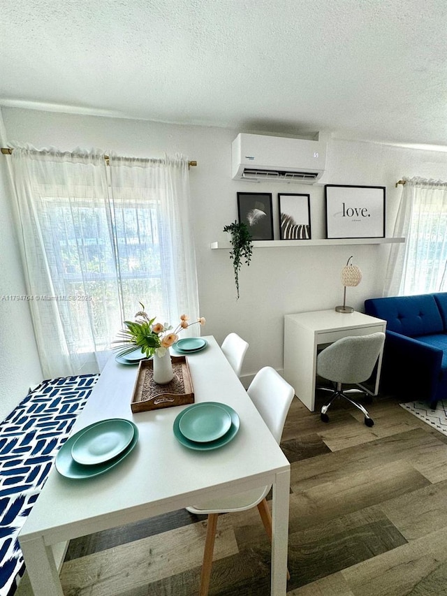 dining space featuring a wall mounted air conditioner, a textured ceiling, and wood finished floors