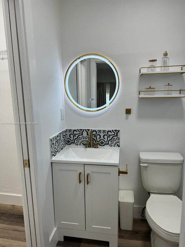 bathroom featuring baseboards, vanity, toilet, and wood finished floors