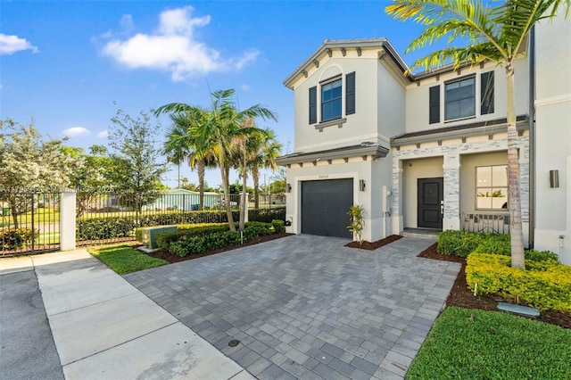 mediterranean / spanish-style home featuring fence, decorative driveway, an attached garage, stucco siding, and stone siding