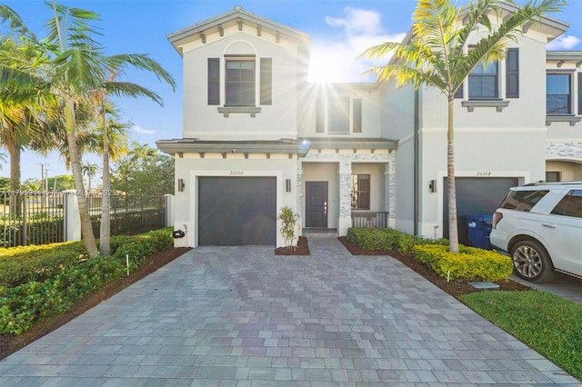 view of front of home with fence, a garage, stucco siding, and decorative driveway