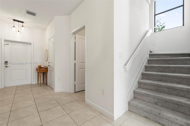 stairway with baseboards, visible vents, and tile patterned floors