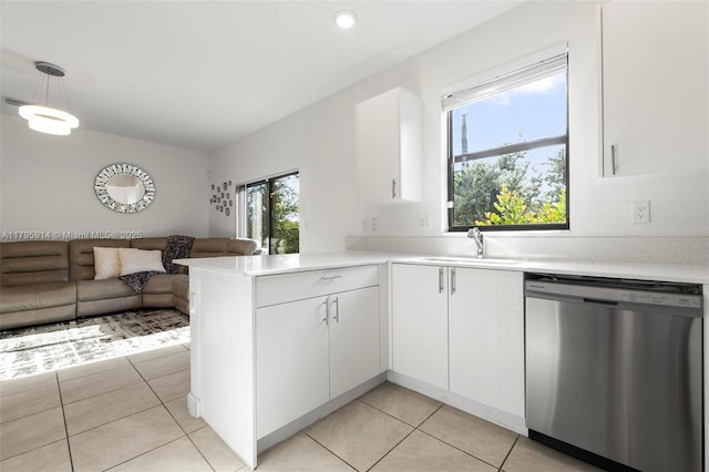 kitchen featuring a sink, a peninsula, open floor plan, white cabinets, and stainless steel dishwasher