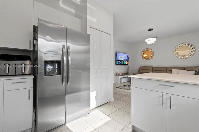 kitchen with pendant lighting, light tile patterned floors, white cabinetry, stainless steel fridge, and light countertops