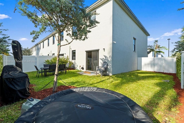 rear view of property with a yard, stucco siding, and fence