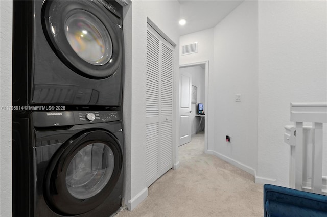 clothes washing area featuring carpet, baseboards, visible vents, laundry area, and stacked washer / drying machine