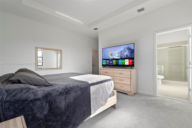 bedroom with light colored carpet, ensuite bathroom, and visible vents