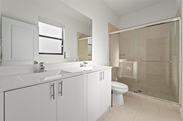bathroom featuring double vanity, toilet, a stall shower, and a sink