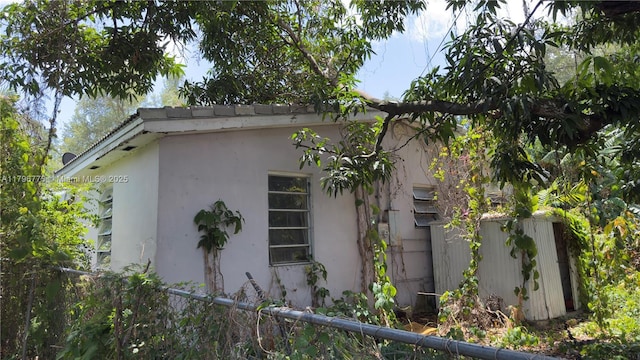 view of side of property with stucco siding and fence